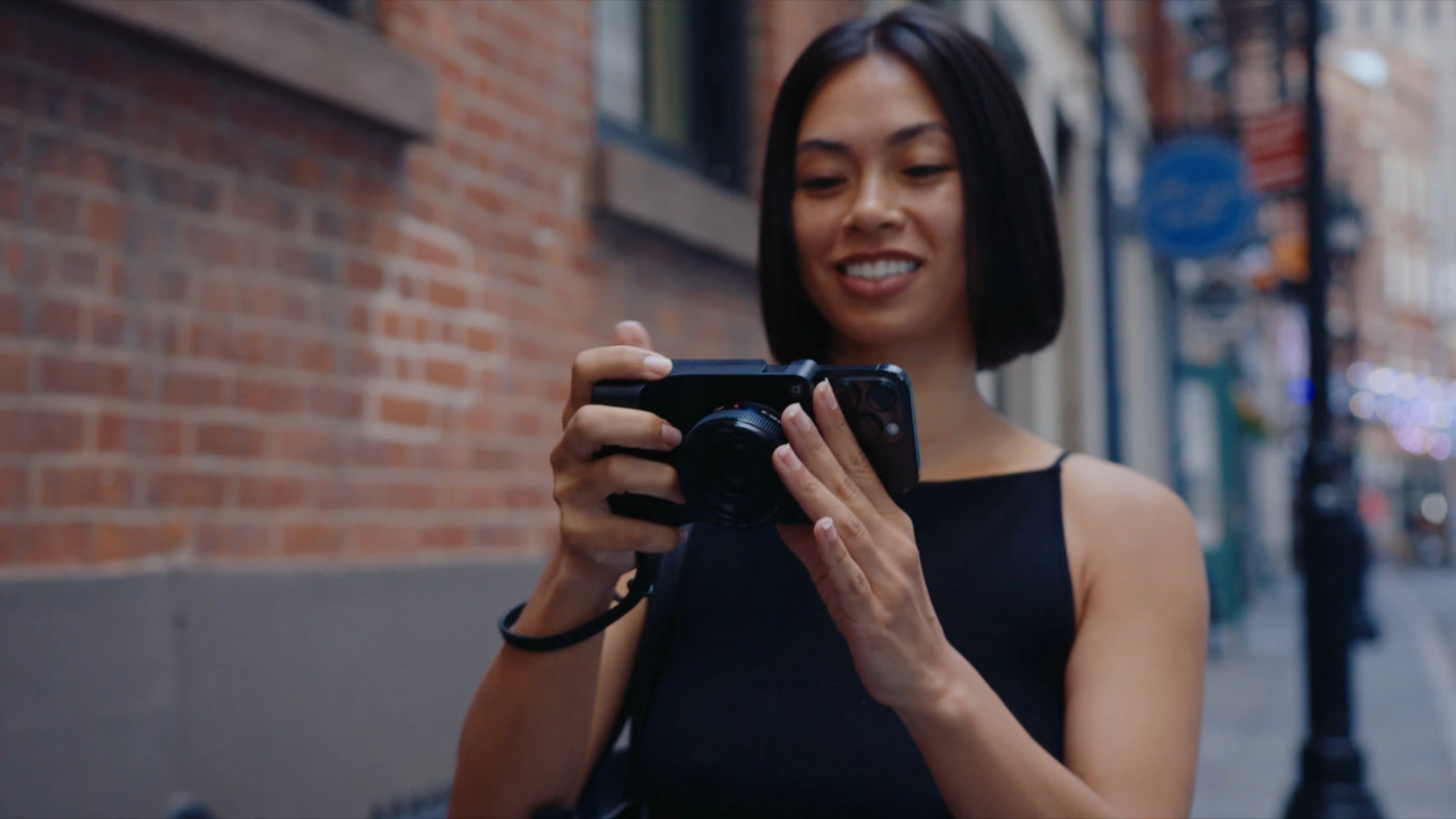 A creator using a Caira mirrorless camera attached to an iPhone