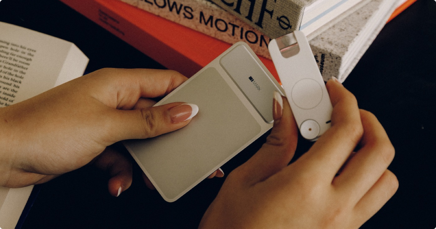 A person holding the Mark II smart bookmark and its card-sized case