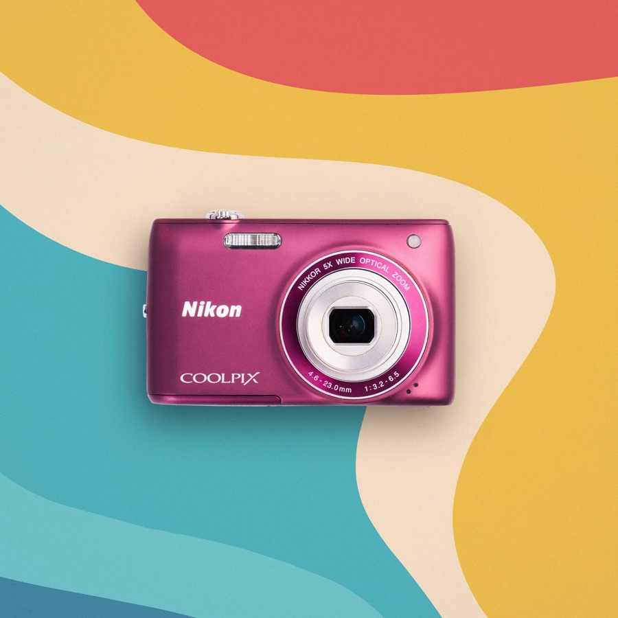 A pink Nikon Coolpix S4100 on a colorful background