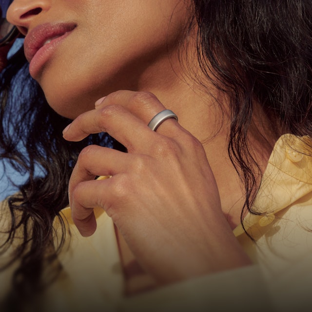 A brushed silver Oura Ring 5 worn on a person's hand